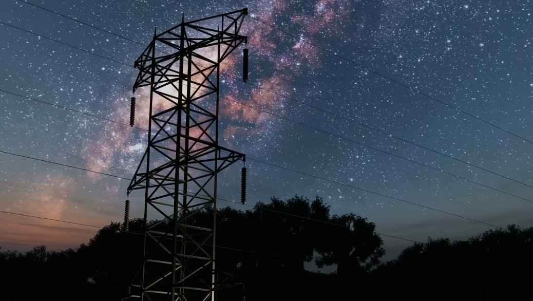 A towering powerline stands sentinel against a night sky ablaze with stars and the Milky Way