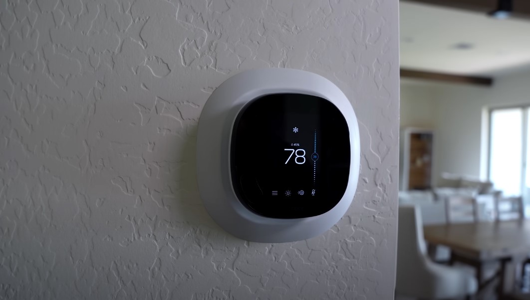 Smart thermostat on a textured wall, displaying a comfortable temperature