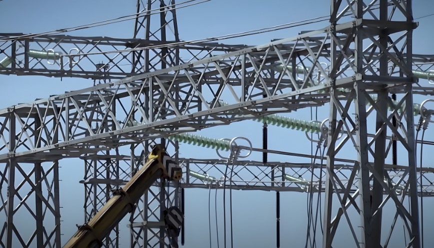 A complex network of metal supports and wires, reaching towards the clear blue sky