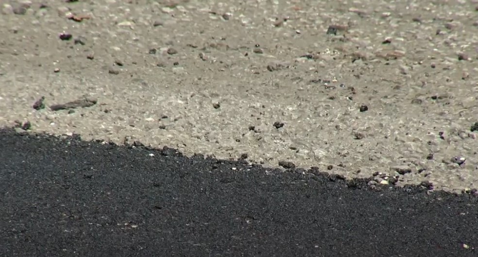 A close-up view of asphalt and concrete pavement meeting